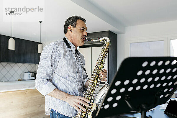Musiker bläst Saxophon und übt zu Hause