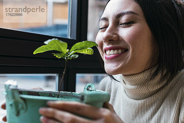 Smiling woman with eyes closed smelling plant