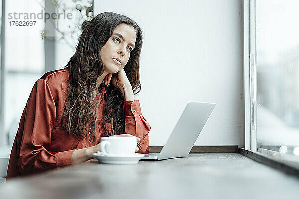 Nachdenkliche Frau mit Laptop im Café