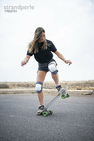 Junge Frau zeigt Geschick mit Skateboard auf der Straße