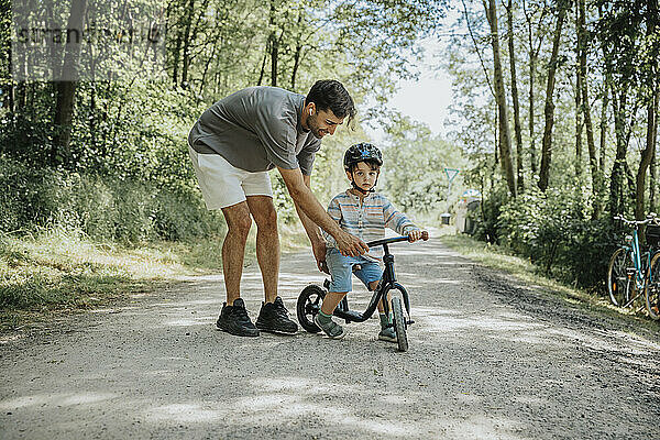 Vater bringt Sohn bei  auf der Straße Fahrrad zu fahren