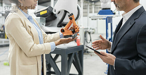 Entwickler zeigt Geschäftsmann in Fabrik Modell eines Roboterarms