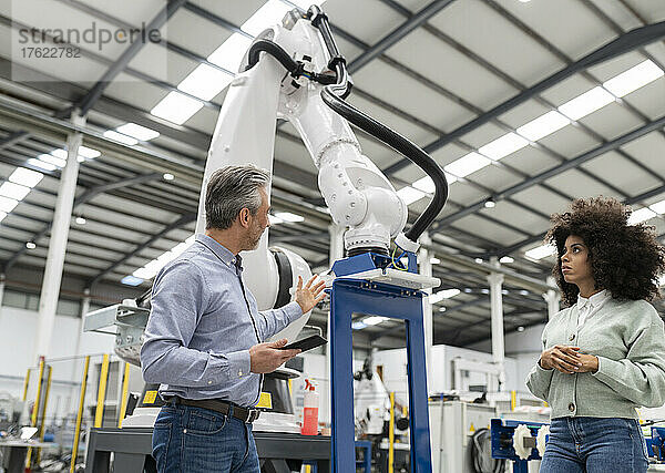 Ingenieur diskutiert über Roboterarm in der Fabrik