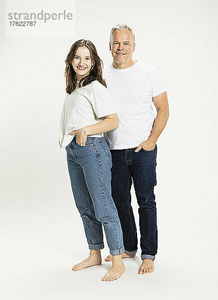 Glücklicher Vater und Tochter stehen mit den Händen in den Taschen im Studio