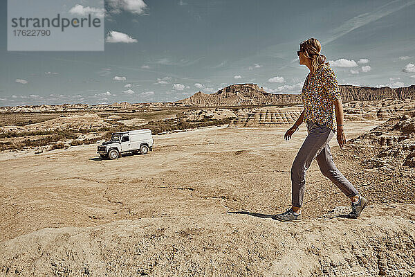 Frau blickt auf ein Auto  das in der Wüstengegend  Bardenas Reales  Spanien  läuft
