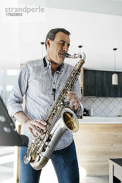 Saxophonist mit geschlossenen Augen spielt zu Hause Saxophon