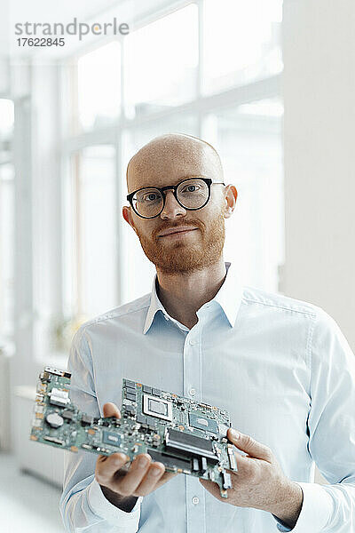 Businessman standing with circuit board in office