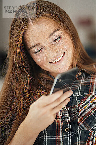 Lächelnde Frau  die ihr Mobiltelefon benutzt
