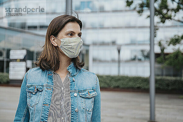 Frau in Jeansjacke mit schützender Gesichtsmaske