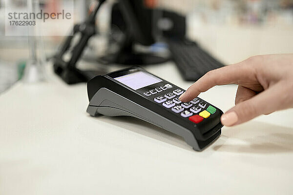 Hand mit Kreditkartenleser an der Kasse im Geschäft