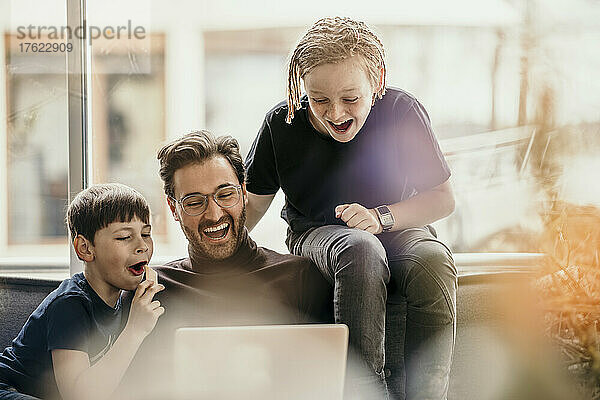 Fröhlicher Vater und Sohn teilen sich zu Hause Laptop