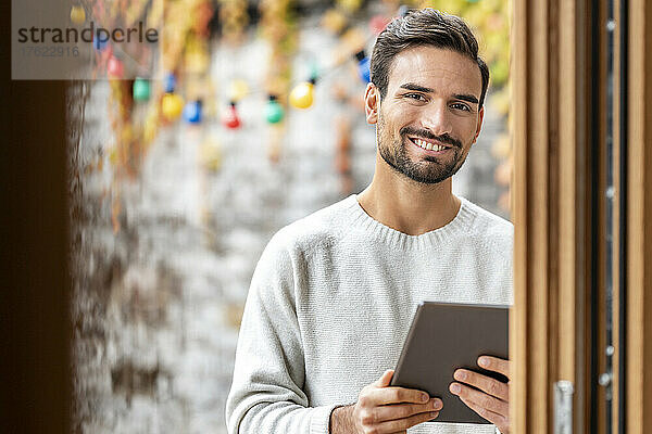 Glücklicher  gutaussehender Mann mit stehendem Tablet-PC