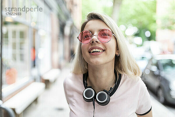 Cheerful teenager with wireless headphones wearing sunglasses