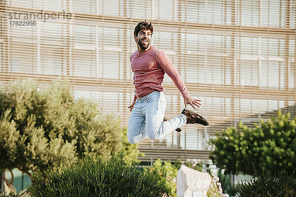 Happy freelancer jumping in front of office building