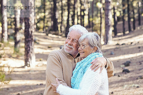 Glückliches älteres Paar  das sich im Wald umarmt