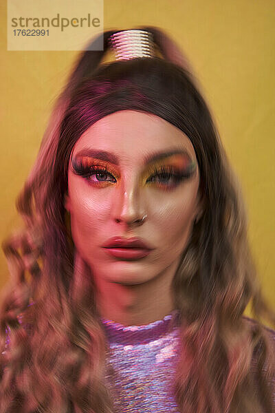 Drag queen with long hair against yellow background