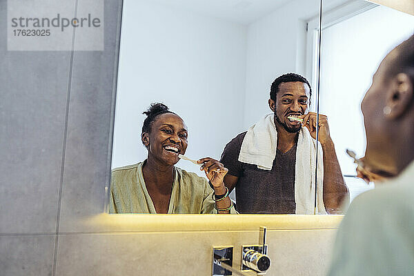 Spiegelbild eines Paares beim Zähneputzen im Badezimmer