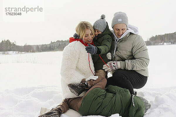Verspielte Familie in warmer Kleidung genießt den Schnee