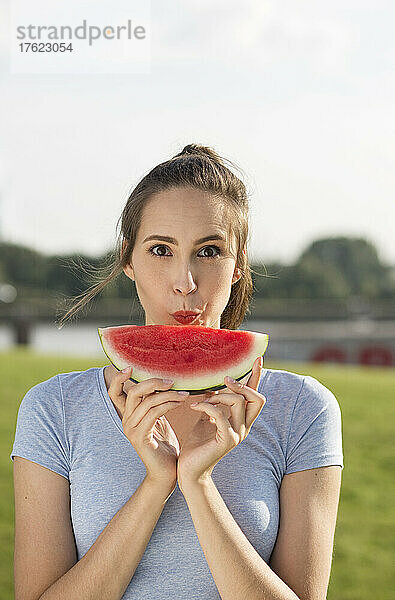 Junge Frau mit einer Scheibe Wassermelone an einem sonnigen Tag