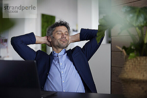 Businessman with eyes closed sitting in office