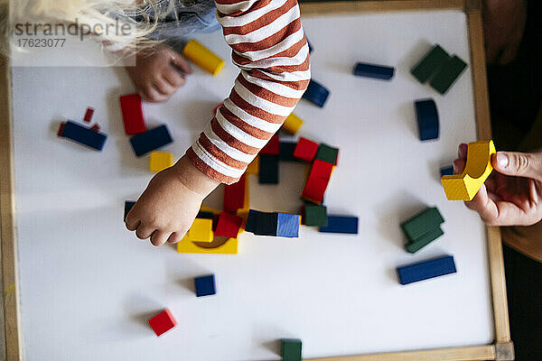 Father and son playing with toy blocks at home