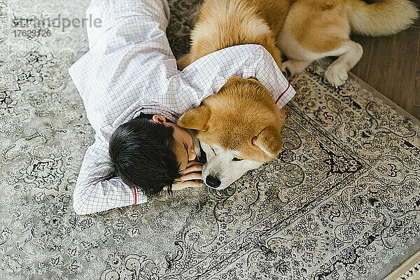 Junge mit Hund auf Teppich zu Hause