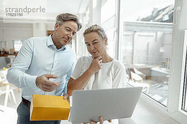 Geschäftsfrau hält Box in der Hand und diskutiert mit Geschäftsfrau am Laptop im Büro