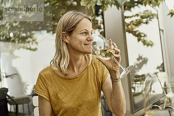 Lächelnde Frau trinkt Wein im Restaurant