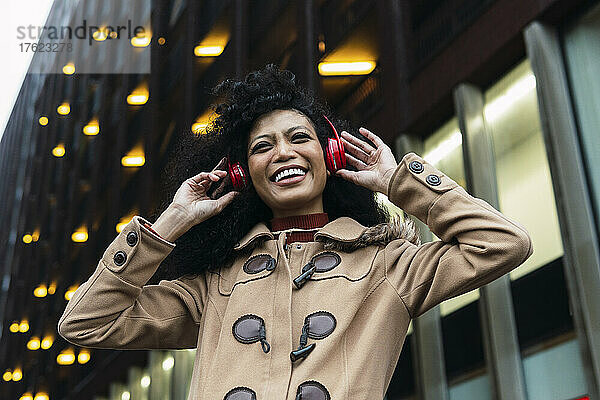 Glückliche Frau hört Musik über kabellose Kopfhörer und genießt die Stadt