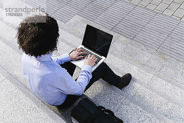 Businessman using laptop sitting on steps