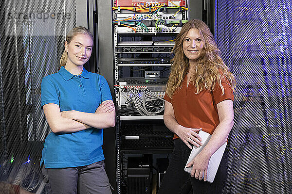 Lächelnde IT-Techniker stehen im Serverraum