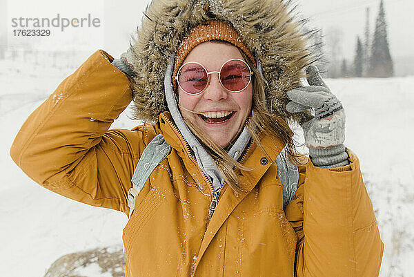 Happy woman in sunglasses and fur jacket enjoying in snow