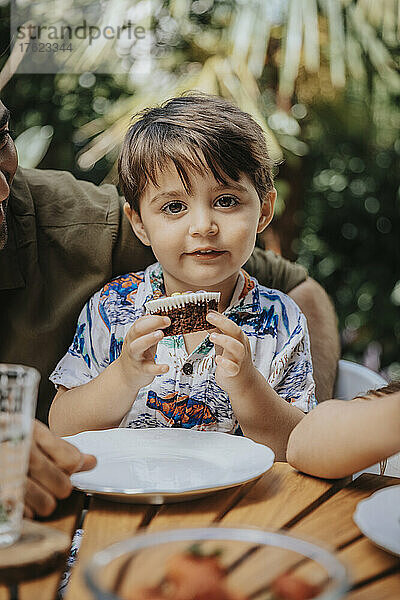 Netter Junge isst Cupcake auf einer Party im Hinterhof