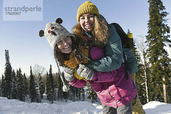 Lächelnde Frau mit fröhlicher Freundin  die den Winter genießt
