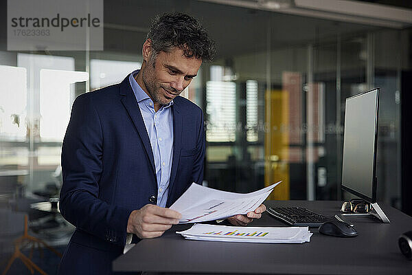 Geschäftsmann liest Dokument am Schreibtisch im Büro