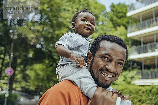 Lächelnder Vater  der seinen Sohn auf seinen Schultern trägt