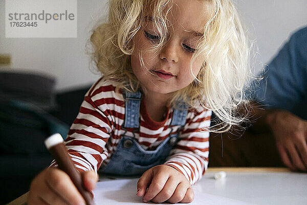 Blonder Junge zeichnet vom Vater zu Hause auf Papier