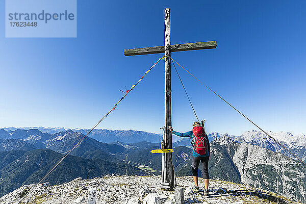 Female hiker touching summit cross of Brunnensteinspitze