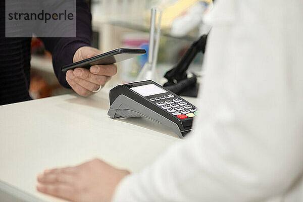 Kunde zahlt kontaktlos per Smartphone an der Kasse im Geschäft