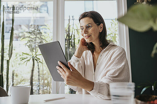 Lächelnde Frau  die zu Hause einen Videoanruf über einen Tablet-PC tätigt
