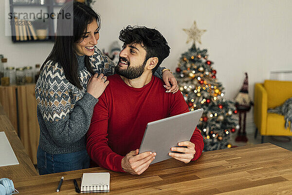Frau mit Freund hält Tablet-PC zu Hause