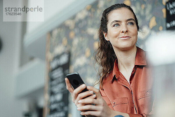 Smiling woman with smart phone in coffee shop