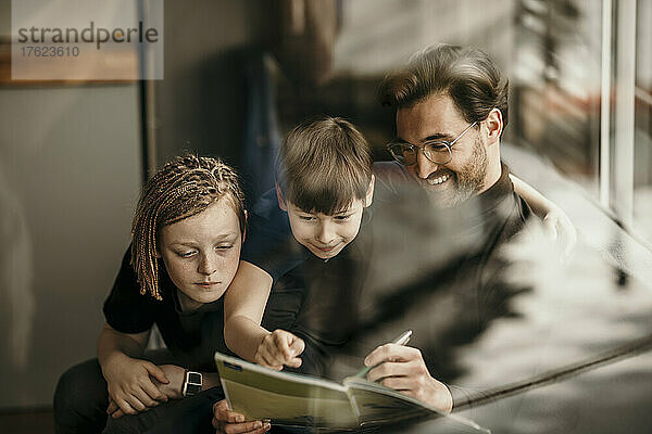 Smiling father explaining to sons learning at home