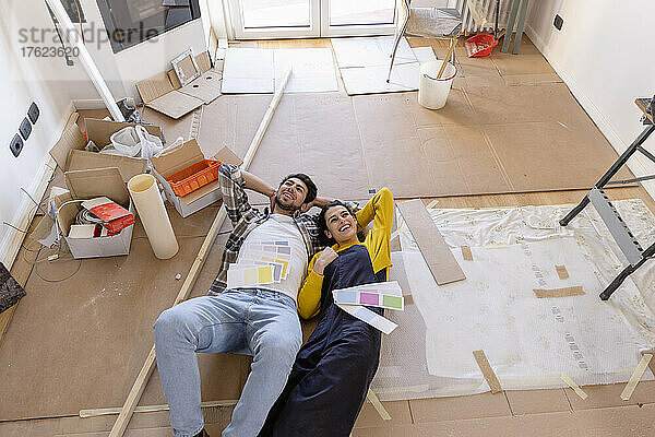 Junges Paar träumt bei Renovierungsarbeiten zu Hause mit Farbmustern