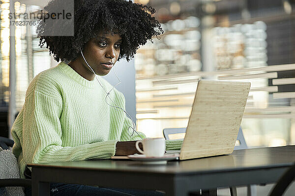Frau sitzt im Café und benutzt Laptop