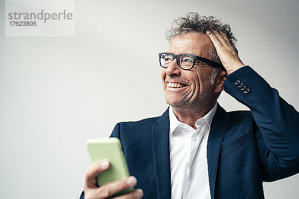 Cheerful businessman with smart phone in studio