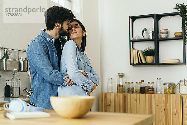 Affectionate couple embracing each other in kitchen