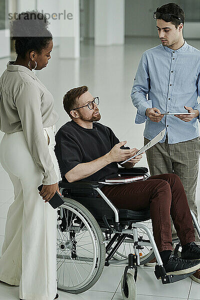 Behinderter Geschäftsmann diskutiert mit Kollegen im modernen Büro