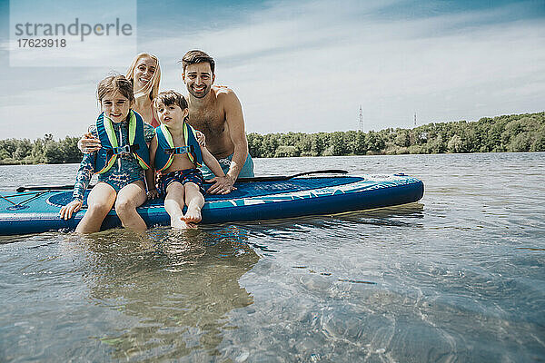 Lächelnde Familie mit Paddleboard im See am Wochenende