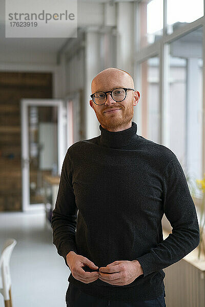 Smiling bald businessman wearing eyeglasses in office